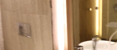 Une salle de bain avec un lavabo blanc, un miroir et des toilettes.