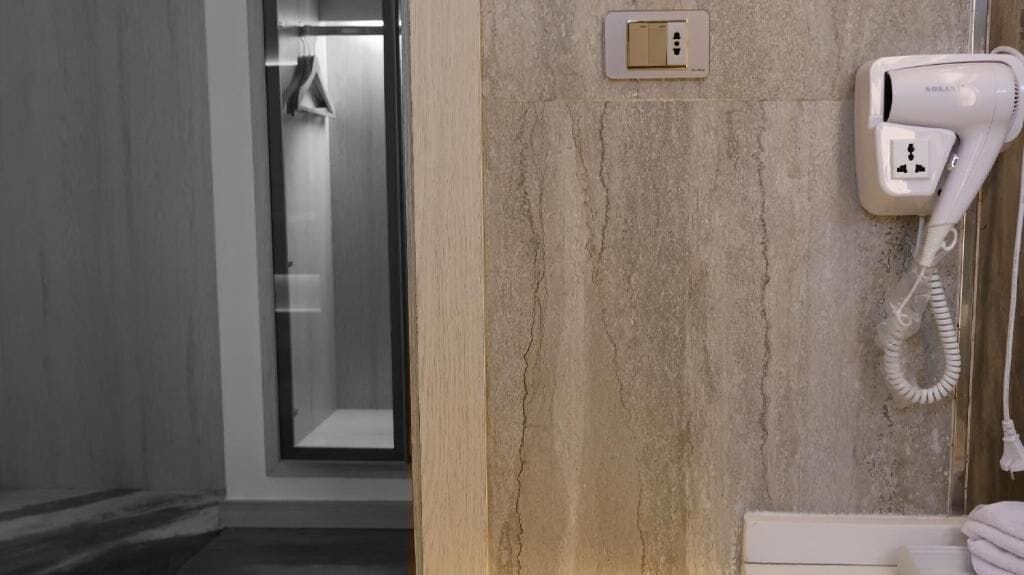 A bathroom with a hairdryer, a towel rack, and a shower area.