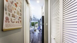 Un couloir doté d’un plancher en bois, d’un ventilateur de plafond et offrant une vue sur l’extérieur.