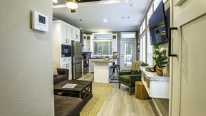 Una cocina moderna con armarios blancos, una isla central y una zona de comedor con una silla verde.