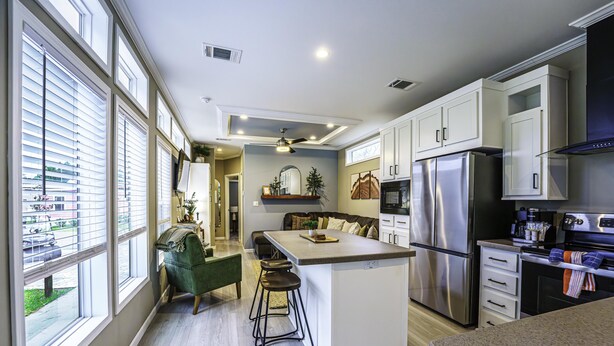 Una cocina moderna con una isla central, electrodomésticos de acero inoxidable y abundante luz natural gracias a amplios ventanales.