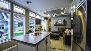 Una cocina moderna con ventanas amplias, una isla central y un refrigerador empotrado.