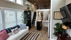 A spacious living room with a high ceiling, a ceiling fan, and a staircase leading to an upper level.