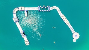 An aerial view of a pier with a boat dock, a lifebuoy, and a person swimming.