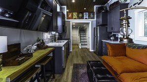 Una cocina compacta con electrodomésticos modernos, un comedor con mesa de madera y un sofá naranja acogedor.