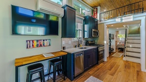A modern kitchen with a wooden countertop, bar stools, and a built-in dishwasher.