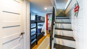 A hallway with a bunk bed, a staircase, and a wall sign indicating auto repairs.