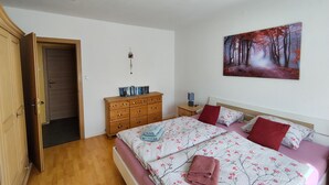 A bedroom with a bed, a nightstand, a dresser, a door, and a painting on the wall. - Eichweg vacation apartment (Bad Sooden-Allendorf)