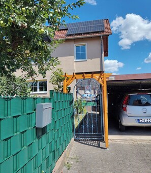 Un immeuble résidentiel doté d’un toit recouvert de panneaux solaires, d’une entrée sécurisée et d’une voiture garée.