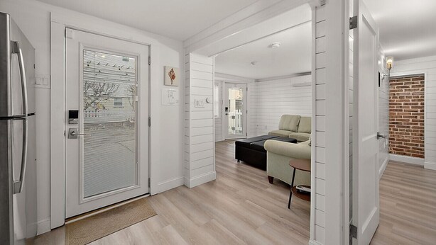 A modern kitchen with a refrigerator, a door with a window, and a wooden floor. - Surf 3 - Steps to beach and OC Boardwalk (Ocean City)