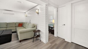 A room with a sectional sofa, a small round table, and a door leading to another room. - Surf 3 - Steps to beach and OC Boardwalk (Ocean City)