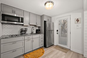 Eine moderne Küche mit weißen Schränken, einem Edelstahlkühlschrank, einer Mikrowelle und einer Kaffeemaschine.