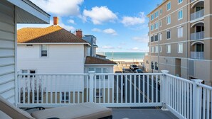 A balcony with a view of the beach and ocean, a white railing, and a lounge chair. - Surf 1 - Steps to the beach and boardwalk (Ocean City)
