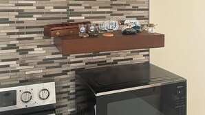 Eine Küche mit modernem Design, inklusive Mikrowelle, Herd und Holzregalen mit diversen Küchenutensilien.