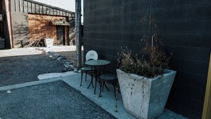 An outdoor seating area with a concrete planter and metal chairs.