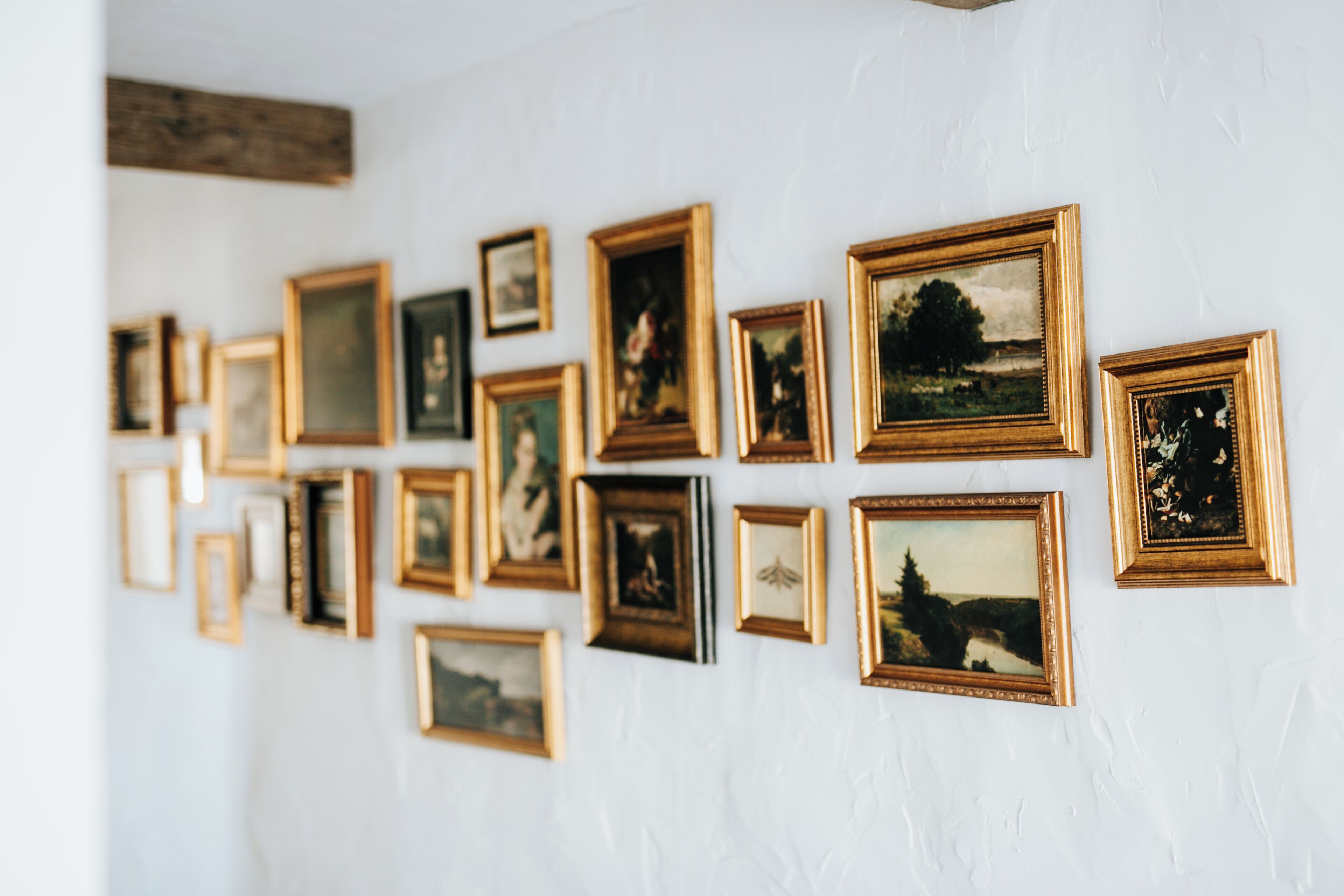 Un mur orné de plusieurs tableaux encadrés, de différentes tailles et de styles variés.