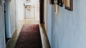 A hallway with a red rug, a white sink, and multiple framed pictures on the wall.