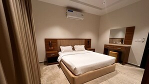 Une chambre d’hôtel avec un grand lit, une table de chevet, une commode, un miroir et un appareil de climatisation.