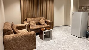 Un salon comprenant un canapé, une table basse et un réfrigérateur.