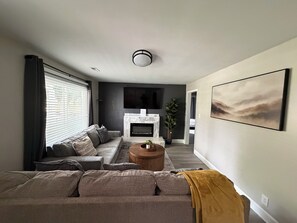 A living room with a sofa, a fireplace, a television, and a painting on the wall.
