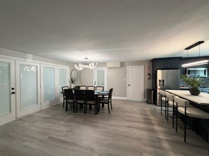 Una cocina moderna con barra, una mesa de comedor y sillas, y una lámpara colgante.