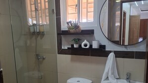 A bathroom with a glass-enclosed shower, a toilet, a sink, and a mirror. - Elegant & Comfortable Apartment with Private Balcony (Santo Domingo Este)