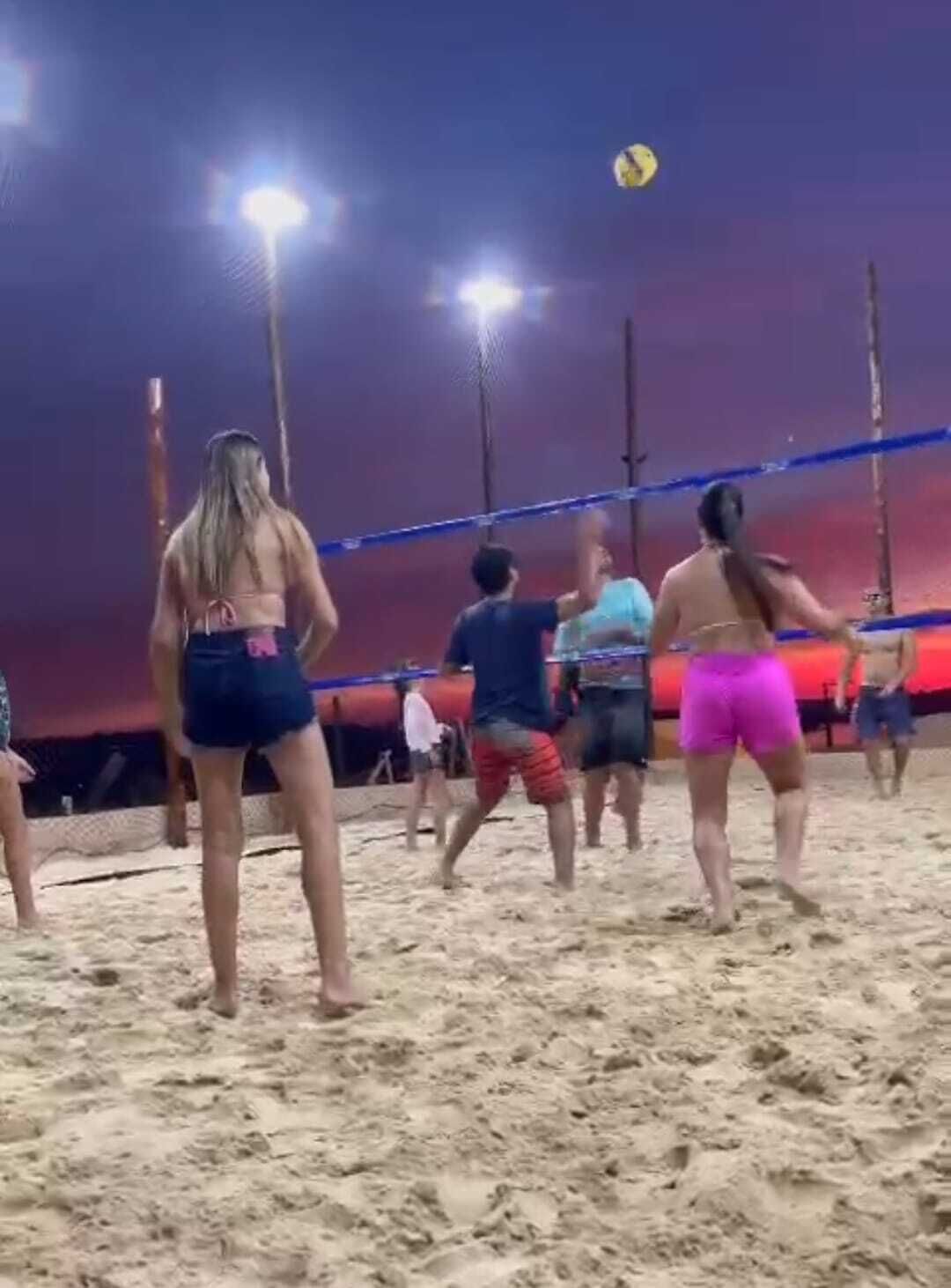 A volleyball game on a sandy court with players in casual beachwear.