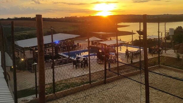 A fenced outdoor area with tables and chairs, likely a patio or dining area, during sunset. - JK Beach Club Bar e Pousada (Ibiúna)
