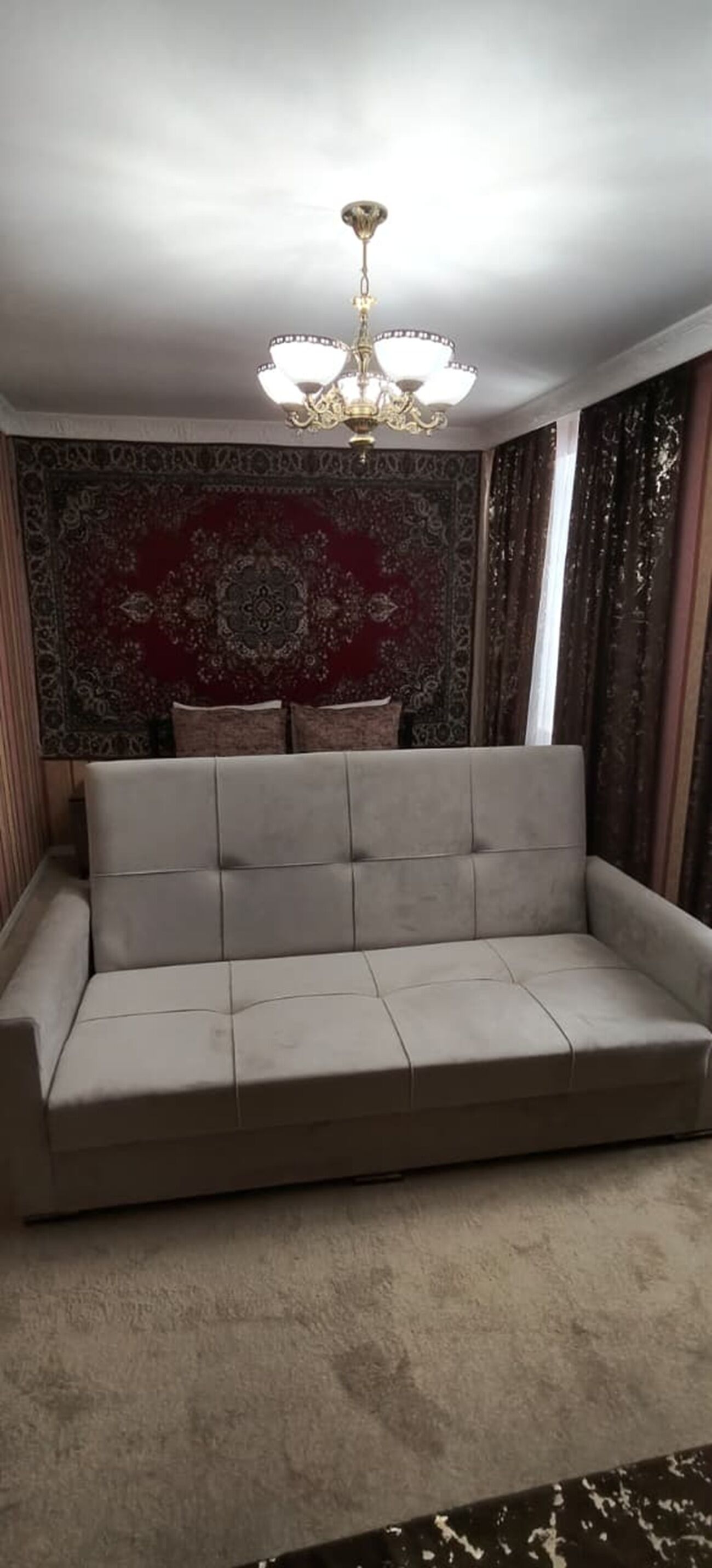 A room with a sofa, a patterned rug, and a chandelier.