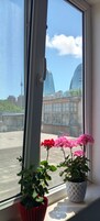 A window with a view of a cityscape, including a tower and modern buildings.