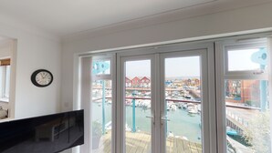 Une pièce dotée d’une grande fenêtre donnant sur un port de plaisance et des immeubles.