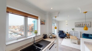 Une cuisine moderne avec une grande fenêtre, un coin repas avec une chaise bleue et une vue sur le paysage urbain.