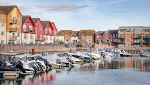 Un port de plaisance où sont amarrés des bateaux, entouré de bâtiments résidentiels aux couleurs vives.