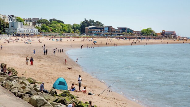 Une plage avec un rivage rocheux, une tente et des gens qui profitent des lieux.