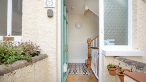 A narrow stairway leading to a landing with a tiled floor, a wooden handrail, and a door with a green frame. - Budleigh Breeze - Three Bedroom Apartment, Sleeps 6 (Budleigh Salterton)