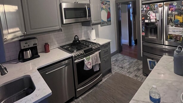 A modern kitchen with stainless steel appliances, grey cabinets, and a marble countertop. - NFL draft come stay at Serene 5-bedroom house with in charming Pittsburgh (Pittsburgh)