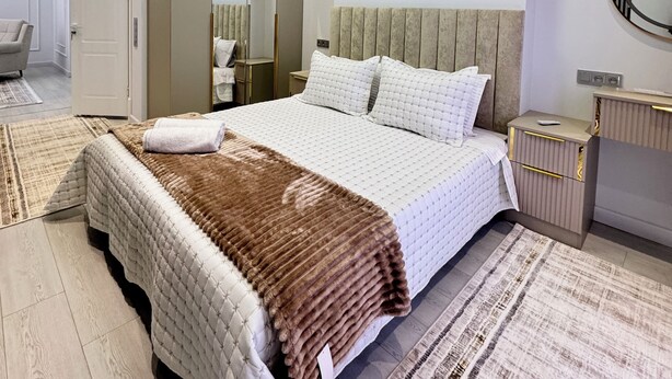 A modern bedroom with a large bed, a bedside table, a mirror, and a wardrobe. - Cozy 2-bedroom condo in lovely Toshkent with AC (Тоshkent)