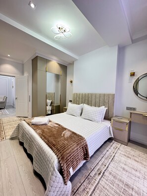 Une chambre à coucher moderne avec un grand lit, une table de chevet, un miroir et une armoire.