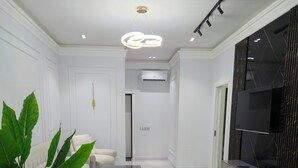 A modern living room with a white sofa, a coffee table, and a large potted plant. - Cozy 2-bedroom condo in lovely Toshkent with AC (Тоshkent)