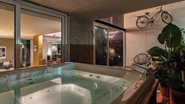 Un bagno moderno con una vasca idromassaggio vetrata, una bicicletta appesa al muro e una grande pianta in vaso.