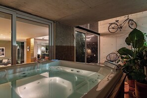 A modern bathroom with a glass-enclosed hot tub, a bicycle mounted on the wall, and a large potted plant. - Luxury 9 Bedroom Villa in Condesa with Rooftop, Jacuzzis, Gym, AC, and Elevator (Mexico City)