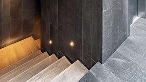 Una moderna scala con pareti in pietra scura e travi in legno.
