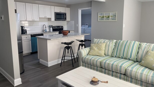 A modern kitchen with white cabinets, a microwave, and a stove. There is a dining area with a white table and a striped green sofa. - 3-bedroom 2 BA Coastal Ranch house New Castle with long driveway (Wilmington Manor)
