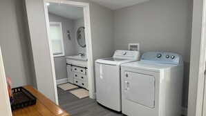A laundry room with a washing machine, dryer, and a small sink. There is a wooden bench and a door leading to another room. - 3-bedroom 2 BA Coastal Ranch house New Castle with long driveway (Wilmington Manor)