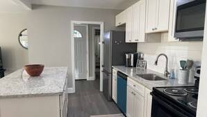 A modern kitchen with granite countertops, white cabinets, a stainless steel refrigerator, a microwave, a dishwasher, and a stove. - 3-bedroom 2 BA Coastal Ranch house New Castle with long driveway (Wilmington Manor)