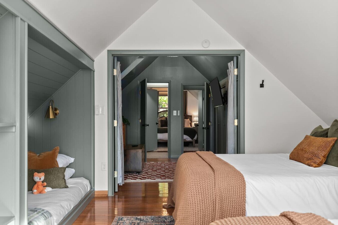 Un dormitorio con una cama grande, una cama más pequeña y un sofá. Hay un pasillo que conduce a otra habitación.