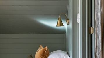 A cozy bedroom with a bed, pillows, a small stuffed animal, a lamp, and a window with curtains.