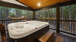 A hot tub on a wooden deck with a view of a forest. - The Gallery In The Pines (Broken Bow)