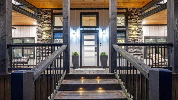 A staircase with stone walls and wooden railings leading to a door. - The Gallery In The Pines (Broken Bow)