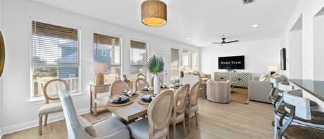A modern dining area with a wooden table, chairs, and a hanging light fixture.